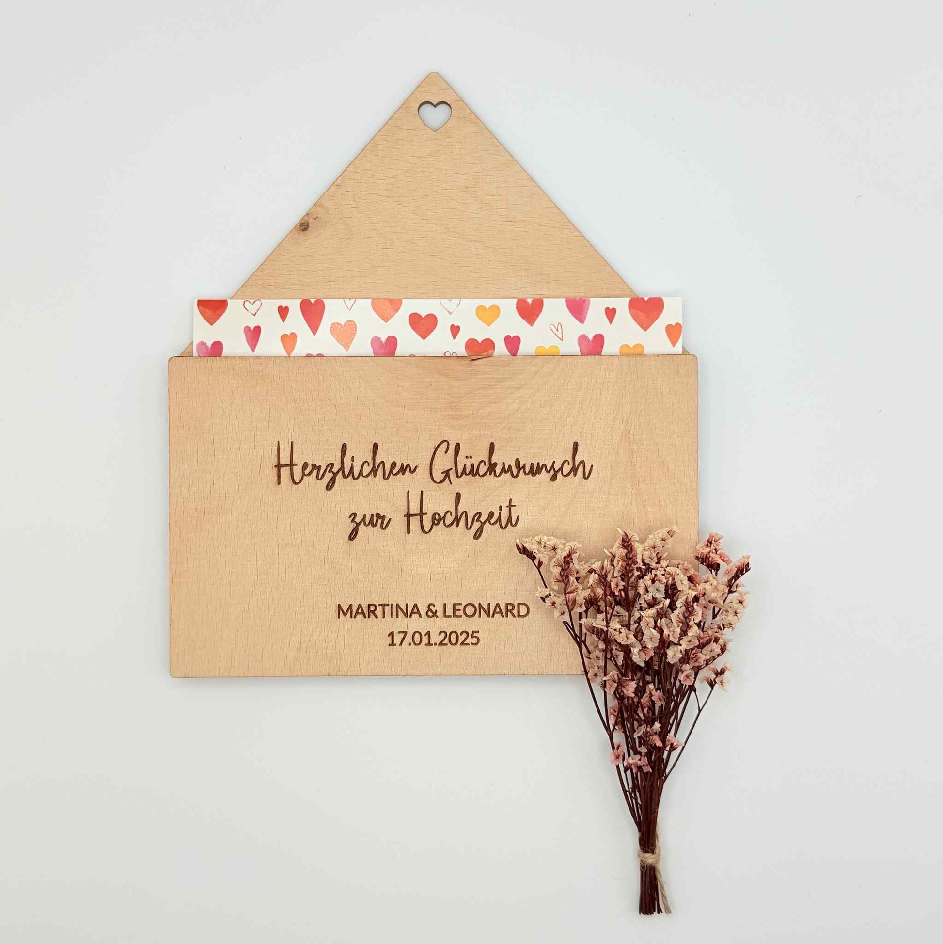 Ein Briefumschlag zur Hochzeit aus Holz mit einer Postkarte und Blumen